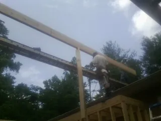 Carpenter setting a ridge beam over a new addition frame — Ice Dam Removal by Roofing Brothers in Boxborough