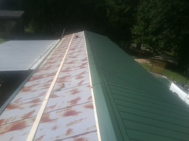 Old rusted panels beside newly installed green metal roofing — Wind Damage Roof Repair by Roofing Brothers in Boxborough