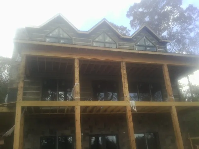 Dormers and porch framing on a large log home under construction — Roof Coating work by our crew in Boxborough