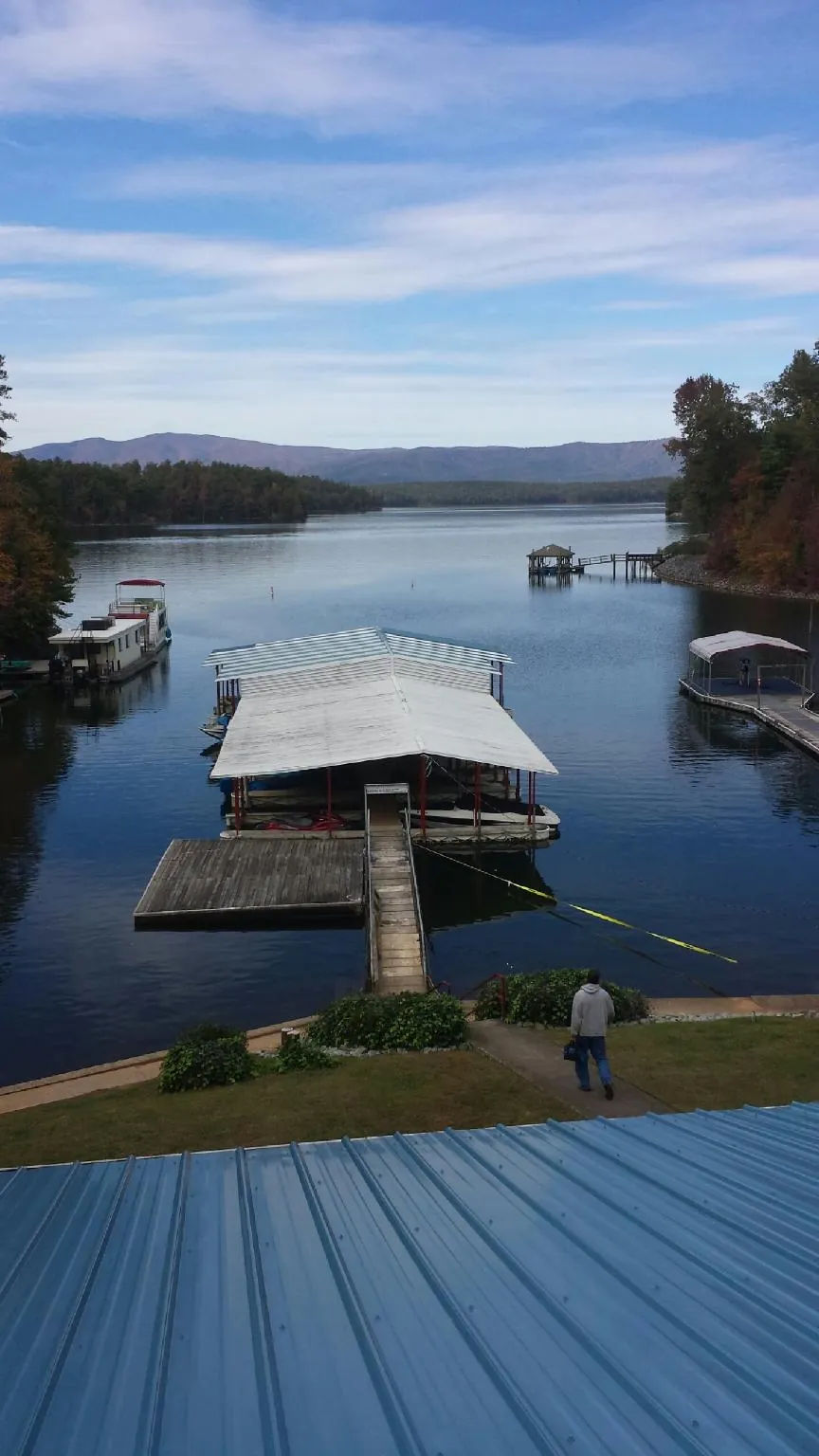View across a lake from a newly installed blue metal roof in Boxborough