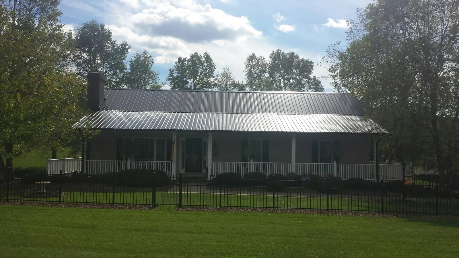 Gray metal roof on a brick ranch with a full width front porch — Gutter Guard Installation work by our crew in Boxborough
