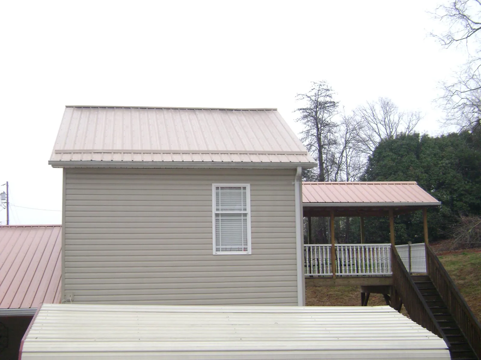 Tan metal roofs on a two story addition and attached porch, from a Roof Replacement job in Boxborough