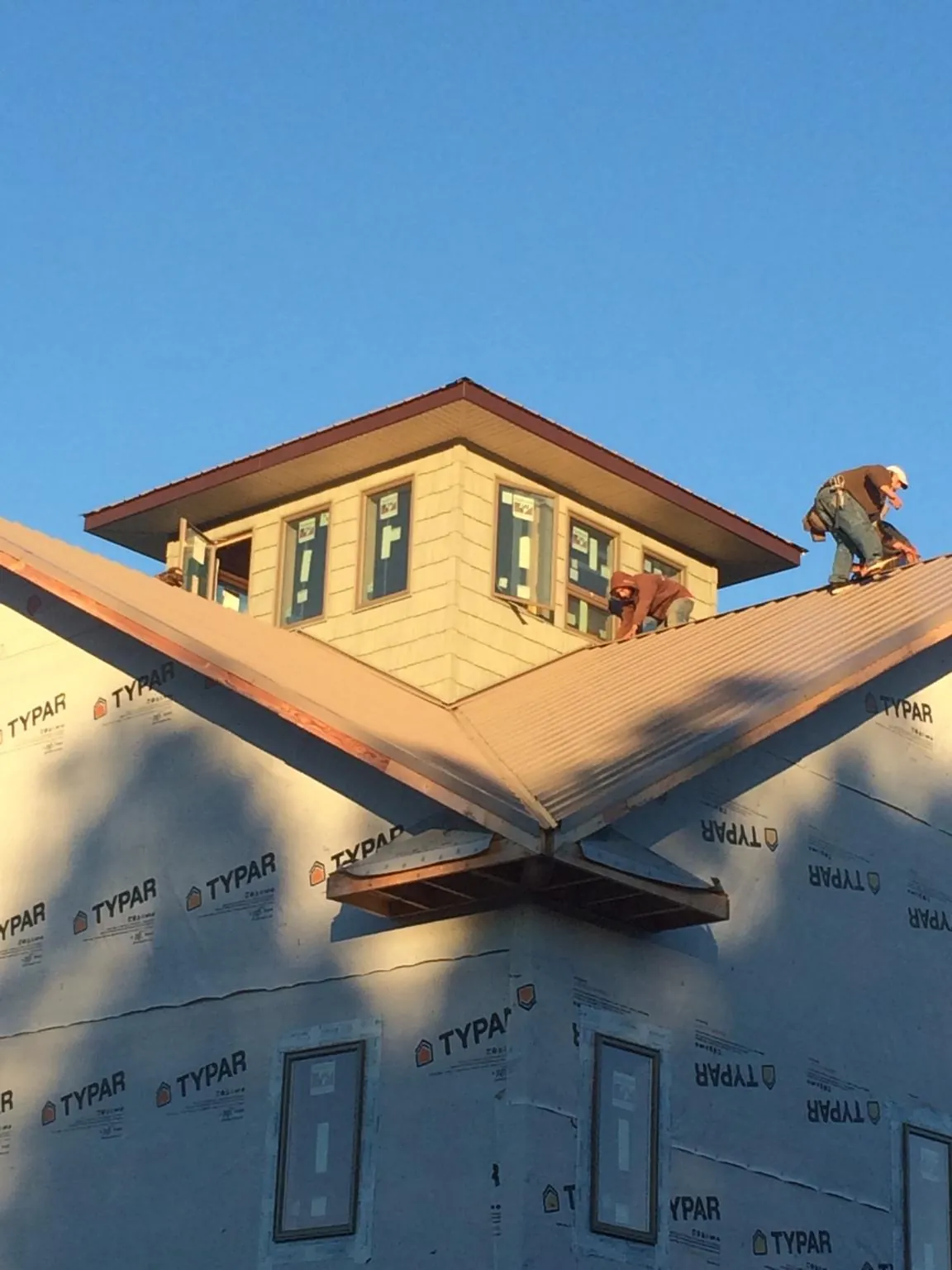 Roofers working around a rooftop cupola on a new metal roof at sunset — Roof Waterproofing in Boxborough by Roofing Brothers